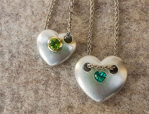 Two heart pendants made of solid silver, with gold-mounted peridot or tourmaline